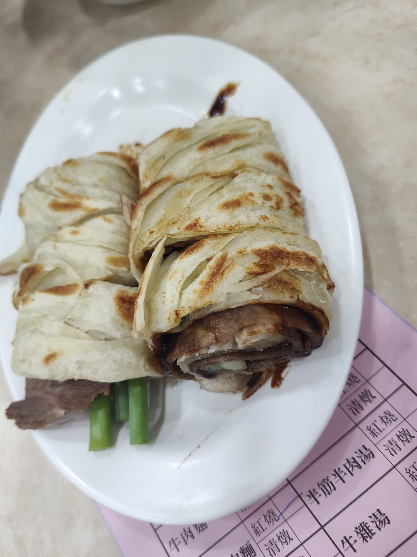 穆記牛肉麵招牌斤餅包牛肉，外皮金黃酥脆，包裹牛肉與青蔥，台北信義區必吃