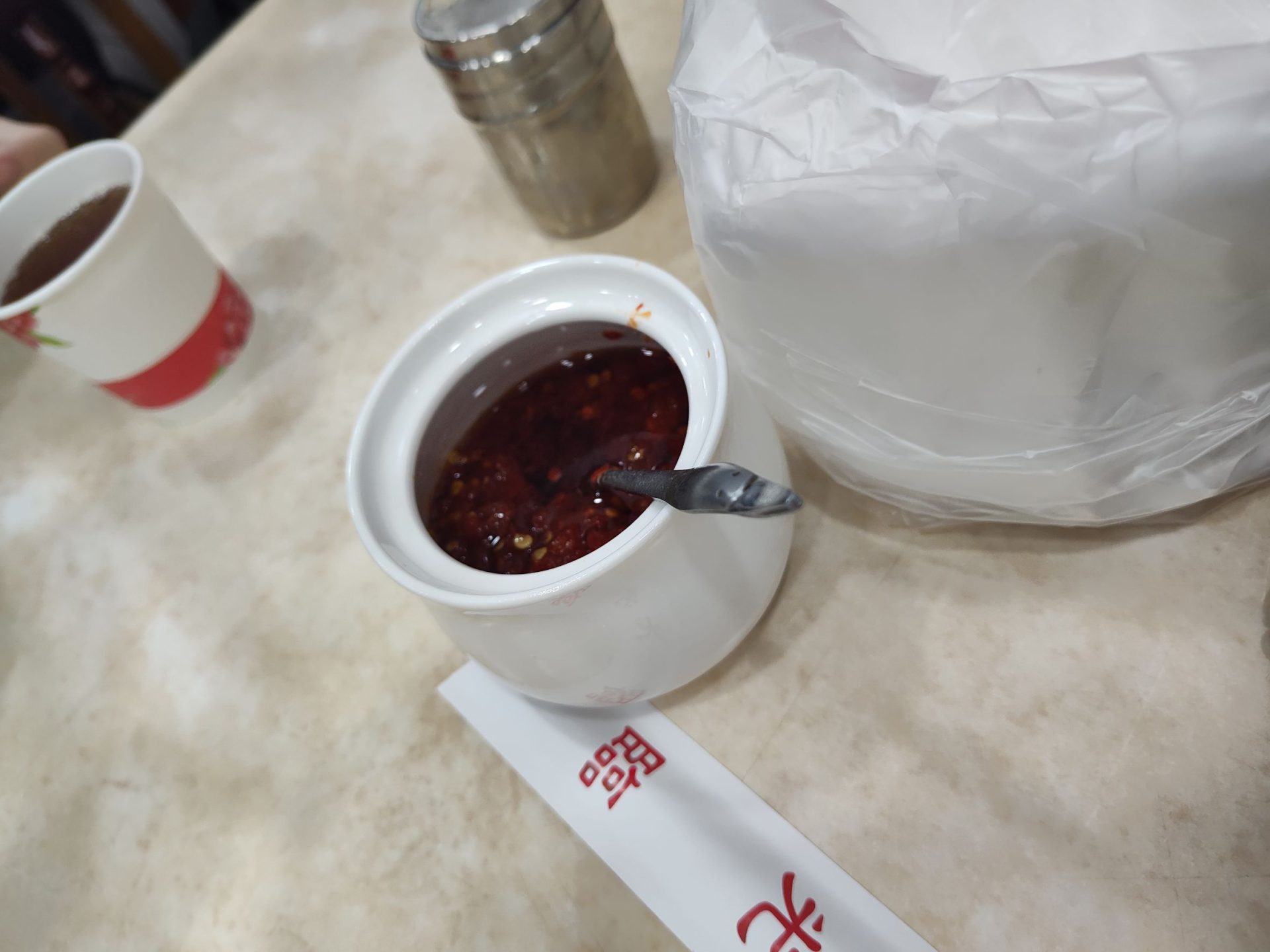 穆記牛肉麵桌上自製辣椒醬特寫，深紅色辣油香氣逼人，可自由添加