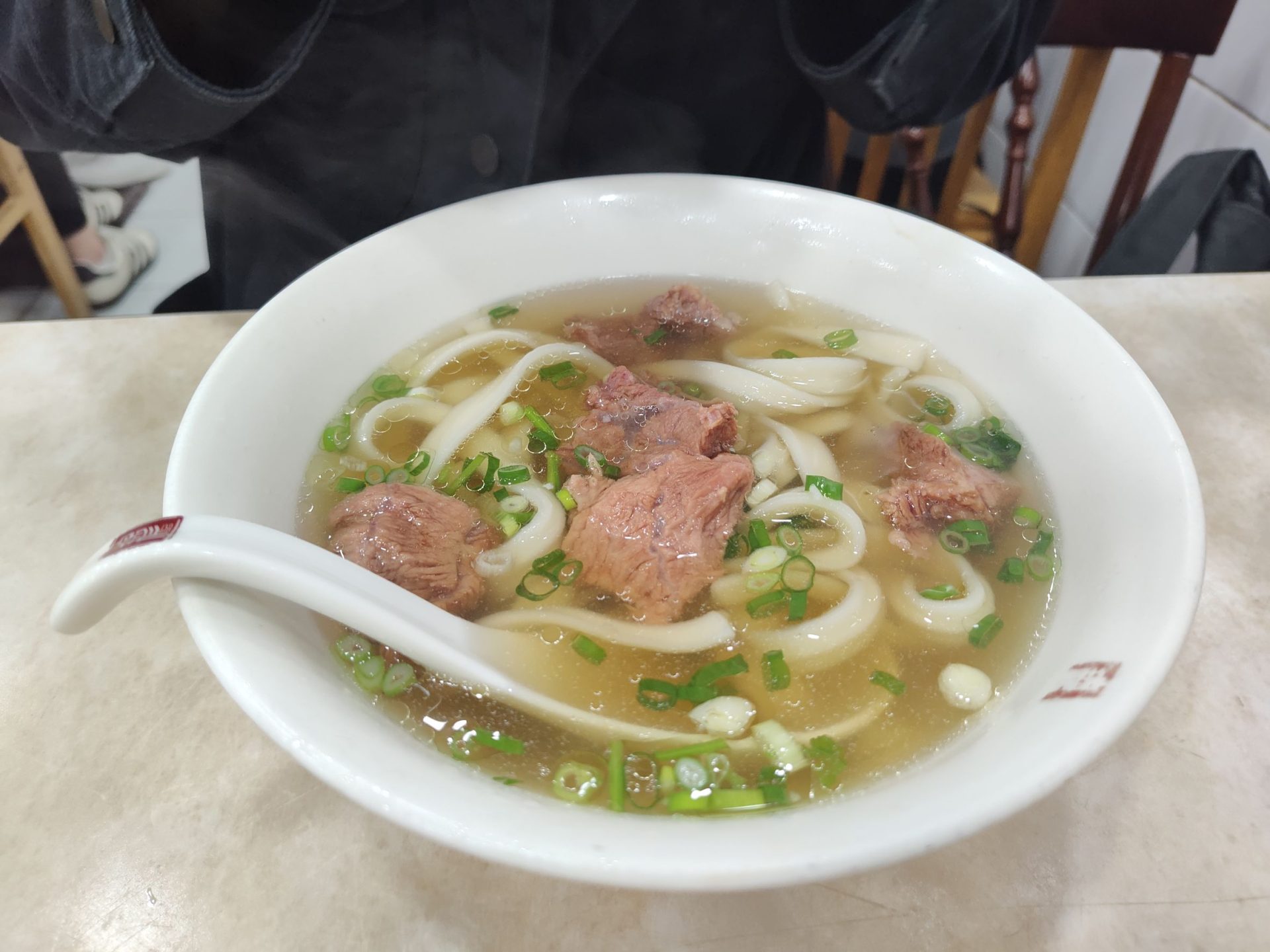 穆記牛肉麵清燉牛肉麵，湯色清澈金黃，大塊牛肉搭配翠綠青蔥，台北信義區老字號