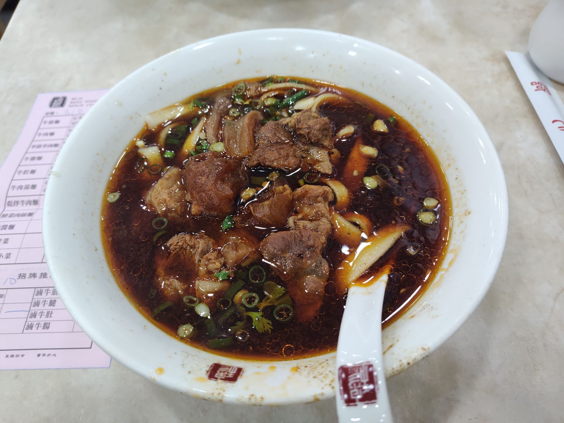 穆記牛肉麵紅燒牛肉麵俯視，湯色深紅油亮，大塊牛肉豐富，米其林必比登推薦