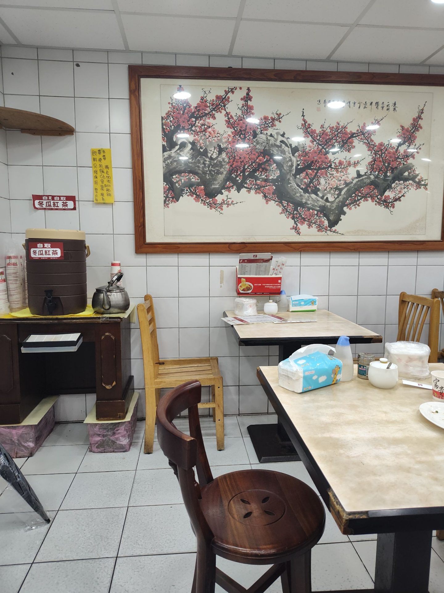穆記牛肉麵用餐環境，白色磁磚牆、木椅、水墨梅花畫，老台北麵館風格