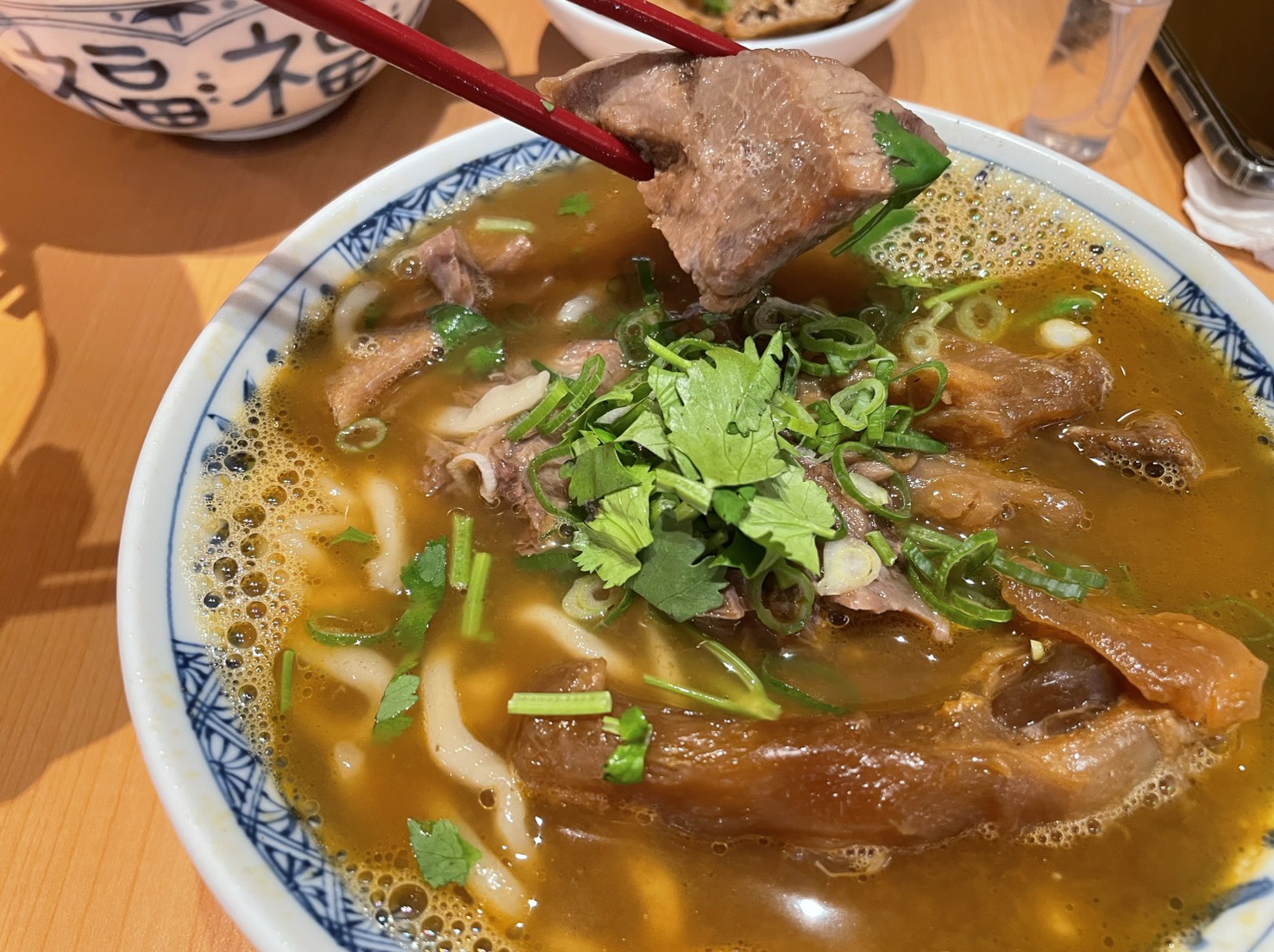 宵夜牛肉麵大王招牌三寶宵魂牛肉麵，筷子夾起軟嫩牛肉，金黃豆瓣紅燒湯頭