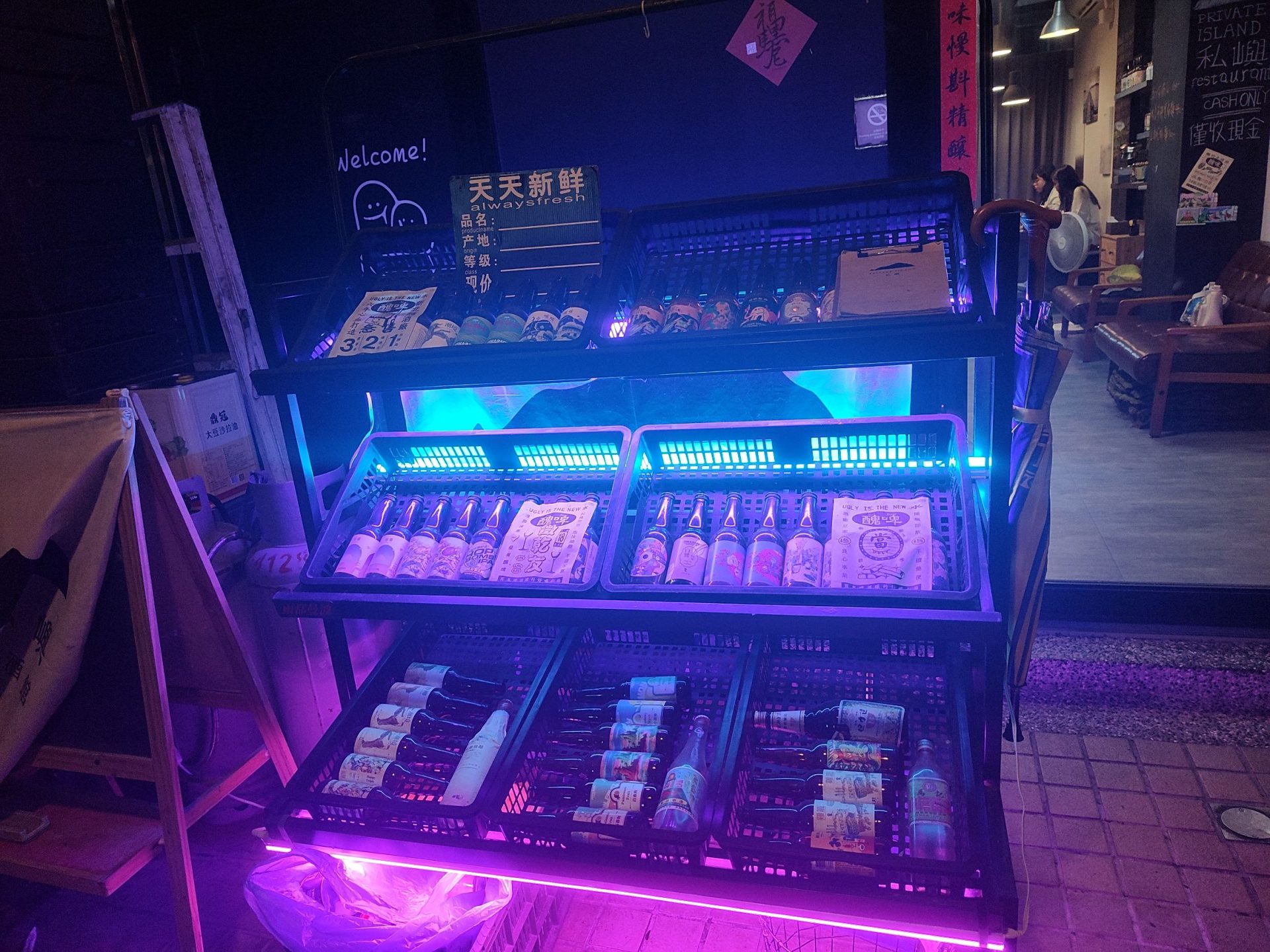 基隆私嶼 private island 店外夜間展示冰箱，藍紫色 LED 燈光照亮飲料
