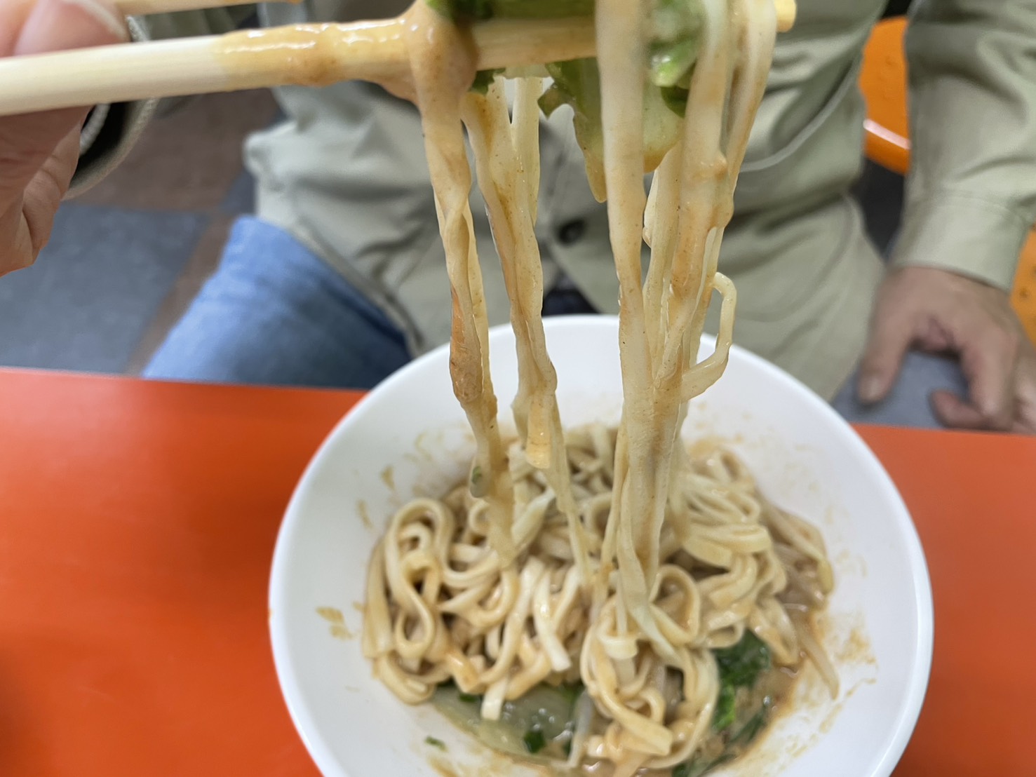 小龍飲食小龍麵用筷子夾起,麻醬沙茶醬汁均勻包覆麵條